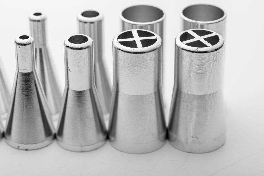 Close-up of stainless steel solder dispensing nozzles on white background, used in automated soldering machines for electronics manufacturing.